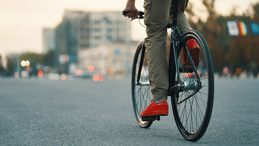 Hombre en biclcieta en la ciudad, practicando ciclismo para aprovechar beneficios