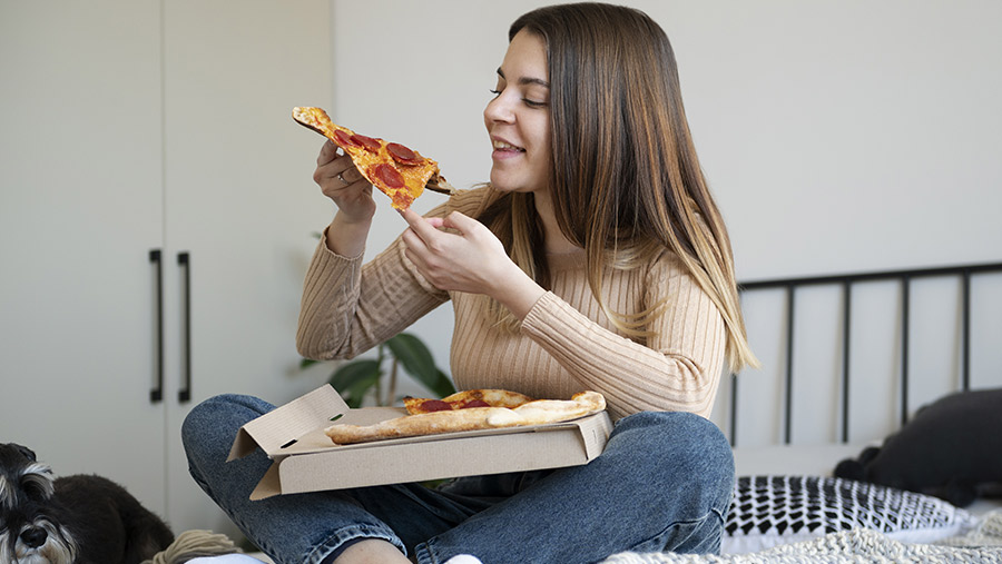 Mujer comiendo pizza en la cama