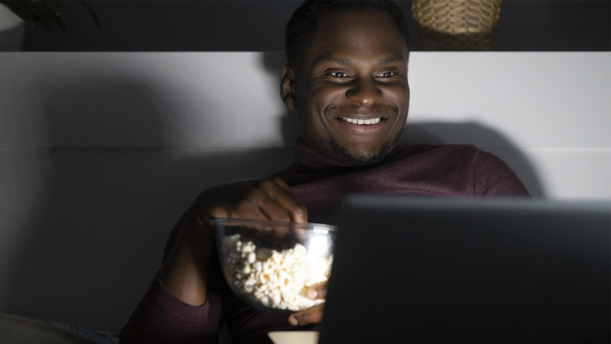 Hombre afroamericano viendo película en su computadora