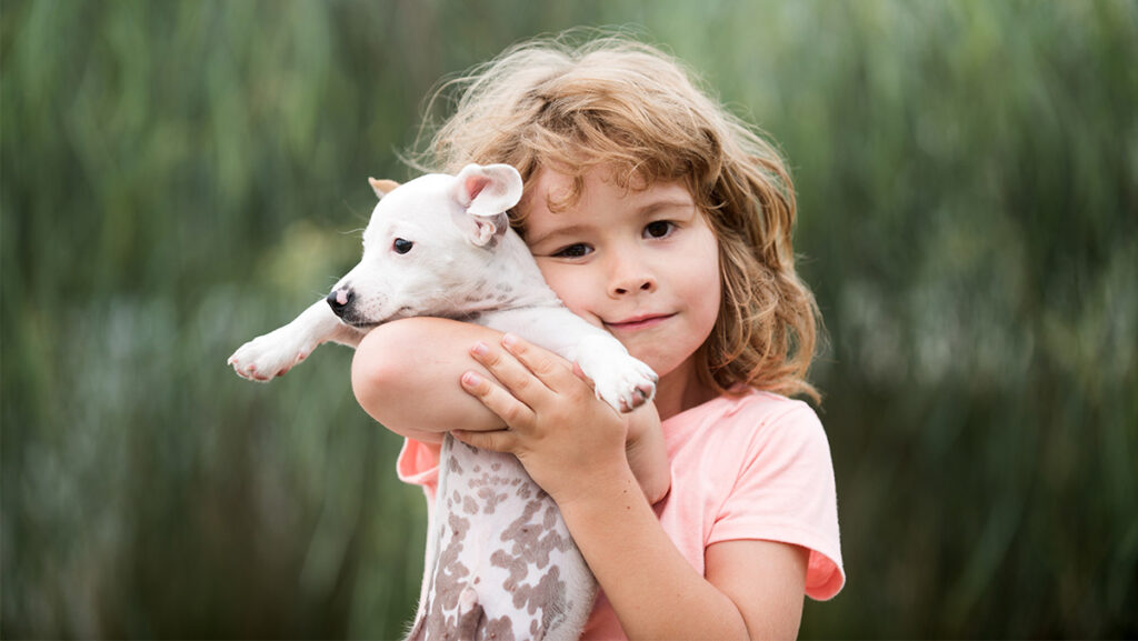 Niña cargando a perrito cachorro