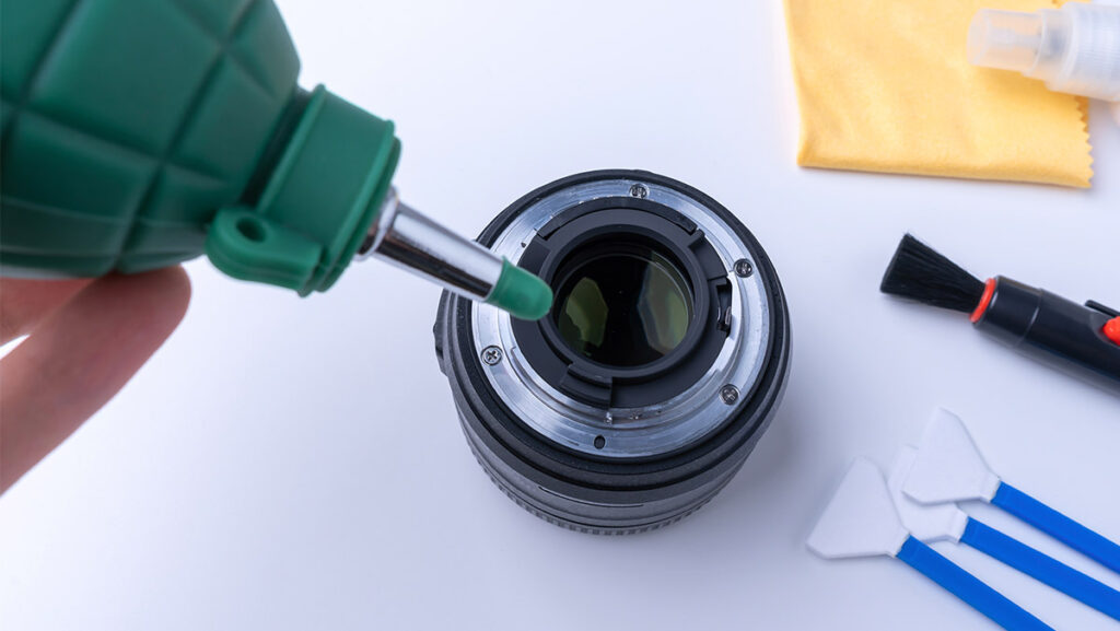 Persona realizando mantenimiento de lente objetivo de cámara fotográfica