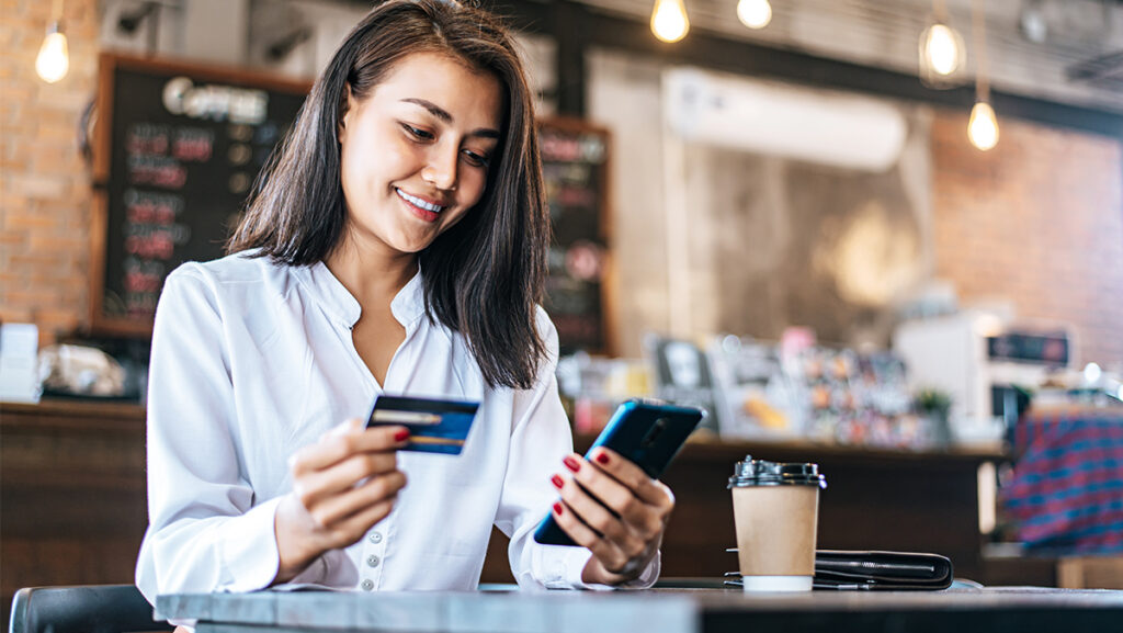 Mujer comprando en línea a través de celular en una cafetería
