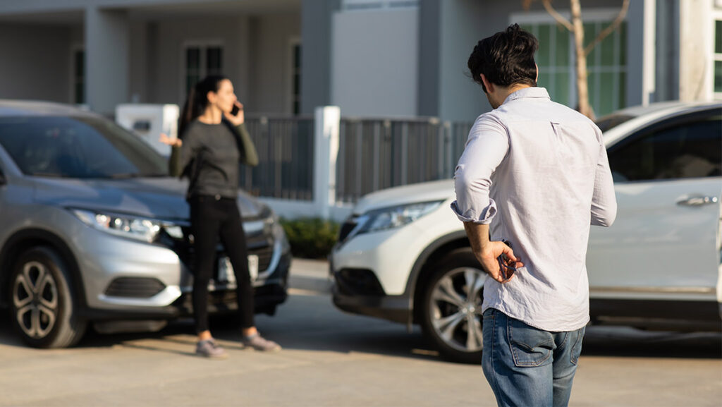 Hombre y mujer hablando al seguro automotriz tras accidente