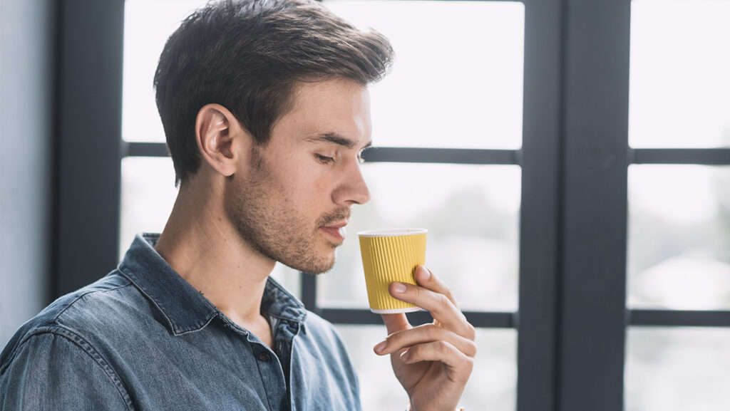 Hombre tomando pequeño vaso con café