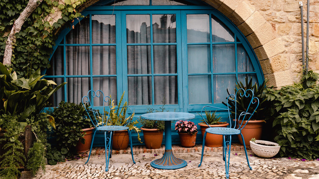 Jardín de casa antigua con dos sillas y una mesita