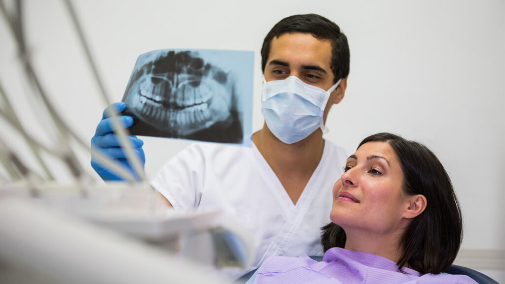 Maxilofacial viendo radiografía con paciente