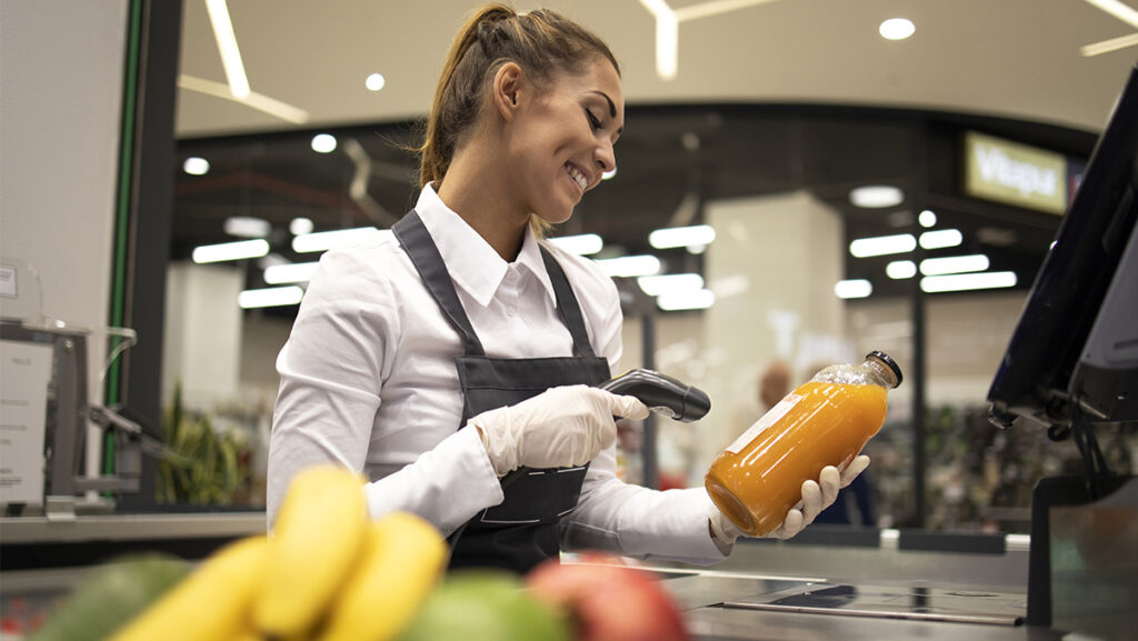 Mujer despachadora de supermercado leyendo código de barras de producto