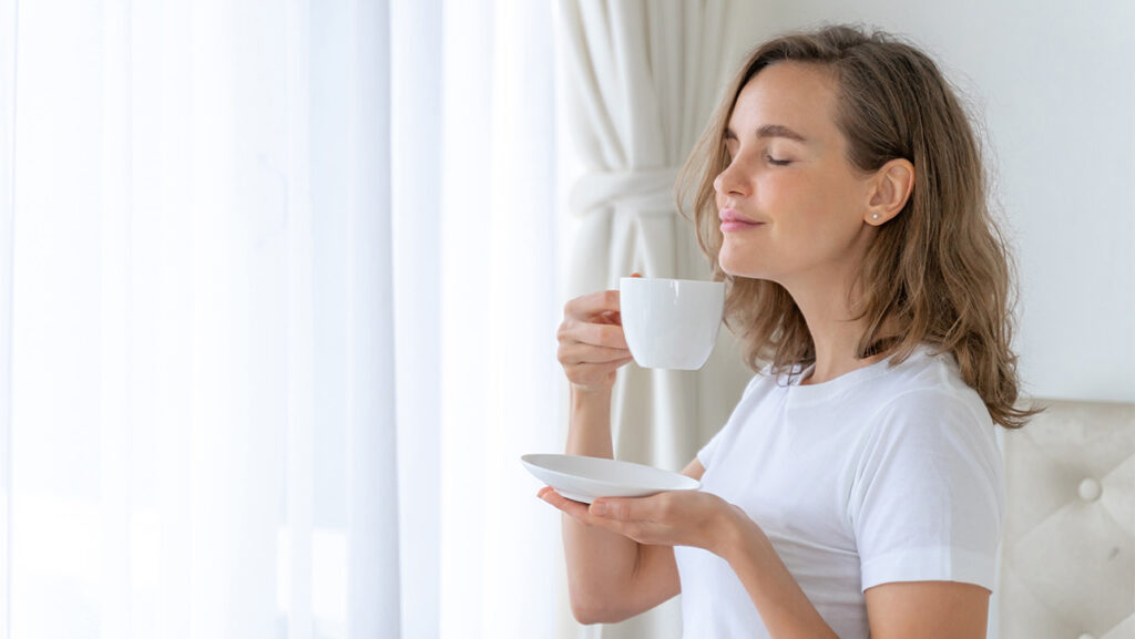 Mujer respirando el aroma de su taza de café