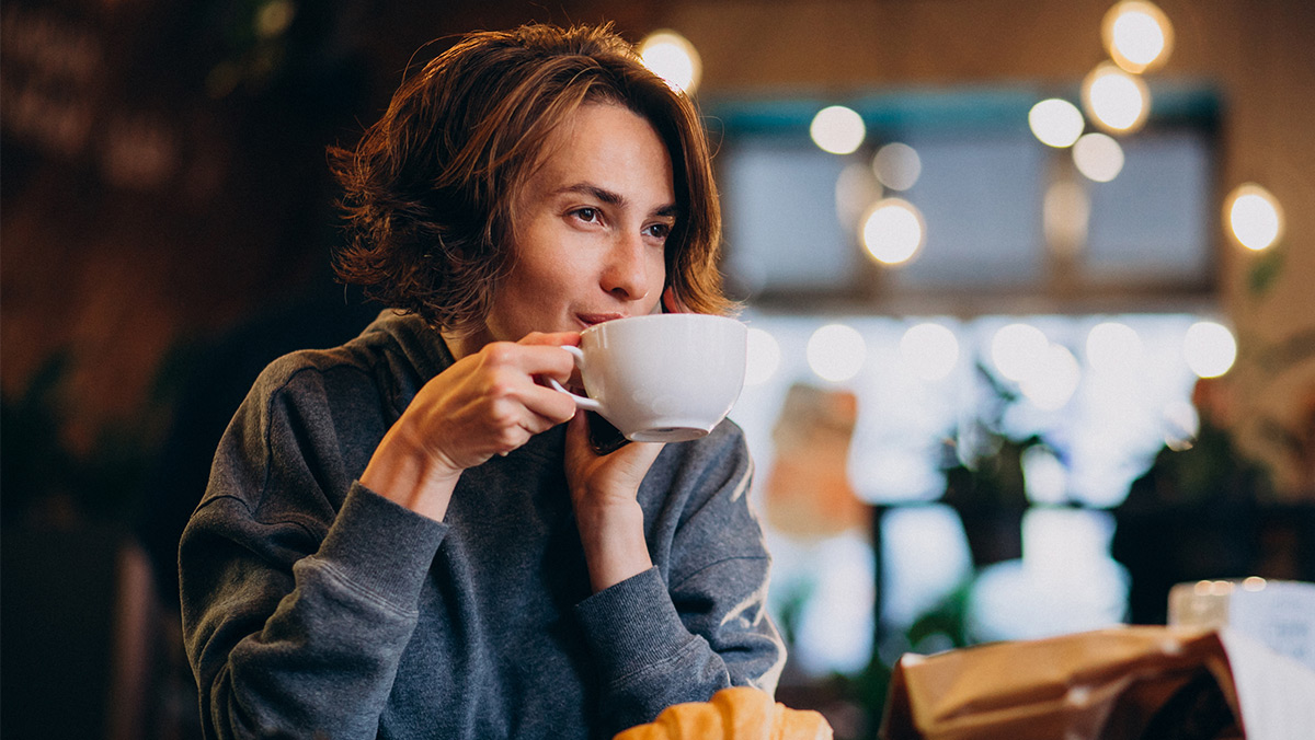 Mujer tomando taza de café en cafetería