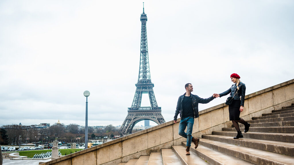 Pareja caminando por escalinatas a los costados de la Torre Eiffel