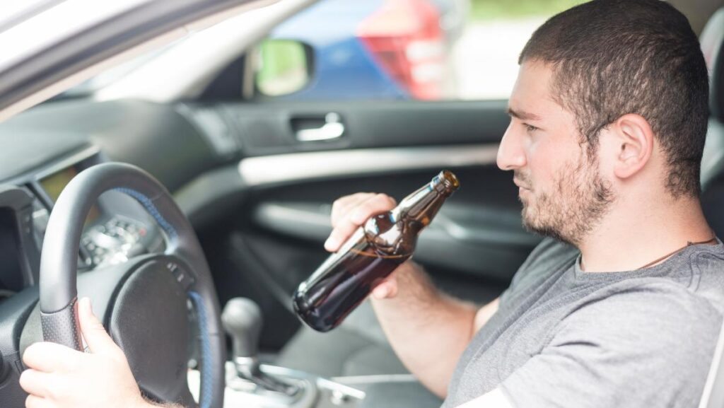 Persona tomando alcohol mientras conduce