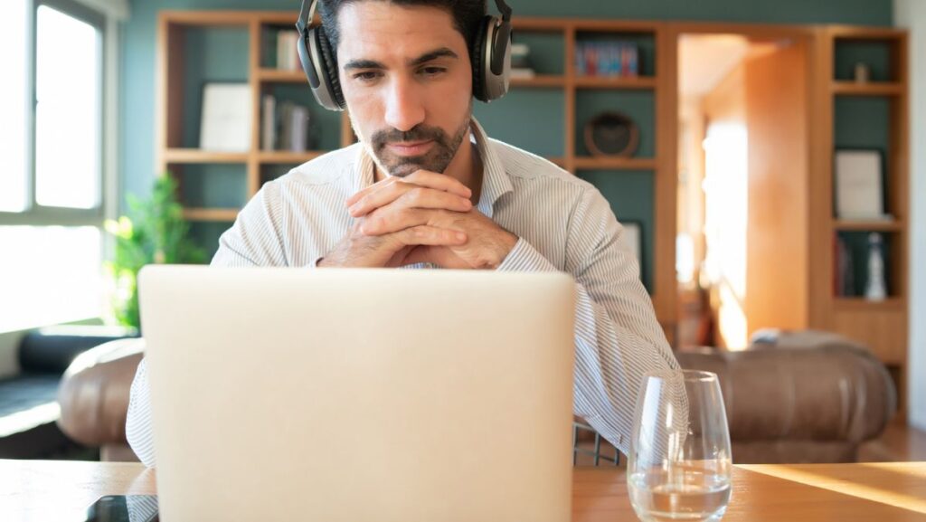 Hombre trabajando en computadora con audífonos