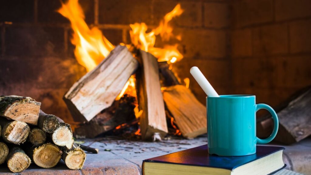 Chimenea encendida de fondo con taza