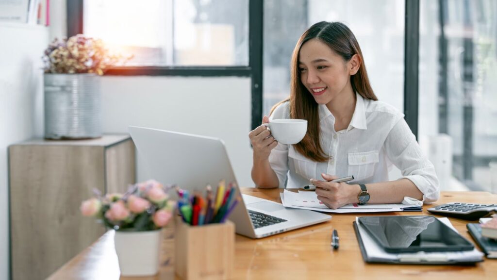 Mujer trabajando en computadora con taza de café