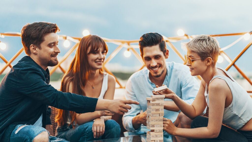 Jóvenes jugando Jenga que entendienron las ventajas de aprender inglés