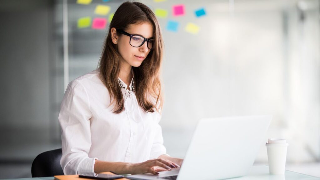 Mujer de lentes atractiva escribiendo en computadora