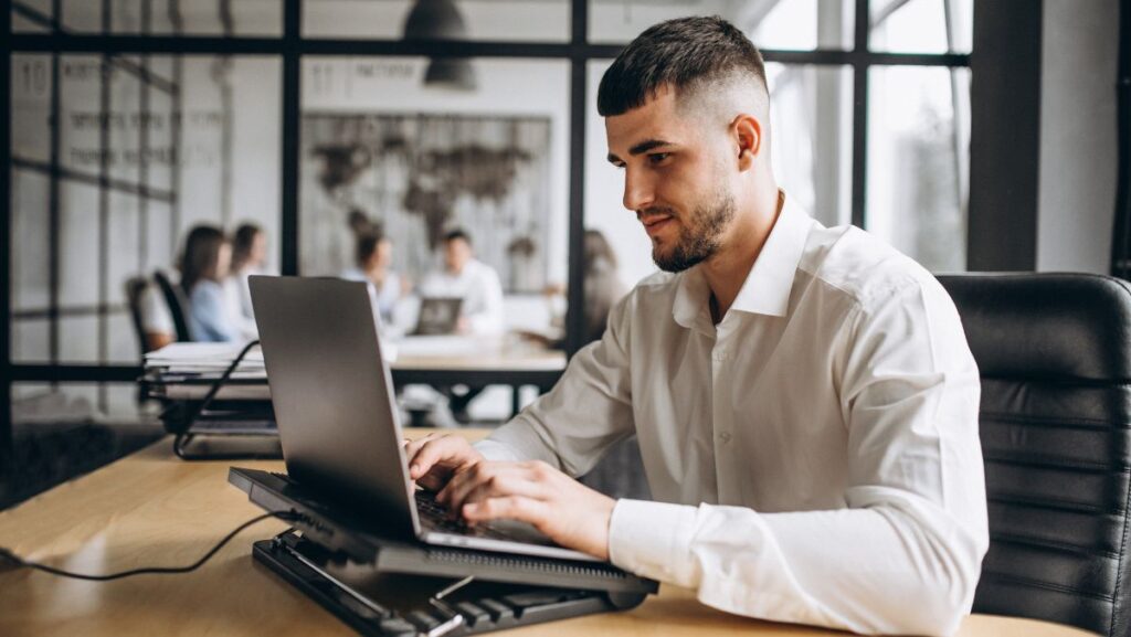 Hombre escribiendo en computadora dentro de una empresa