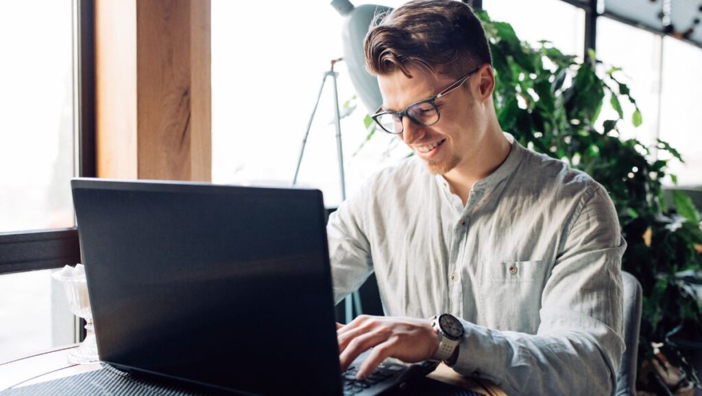 Hombre sonriente escribiendo en computadora