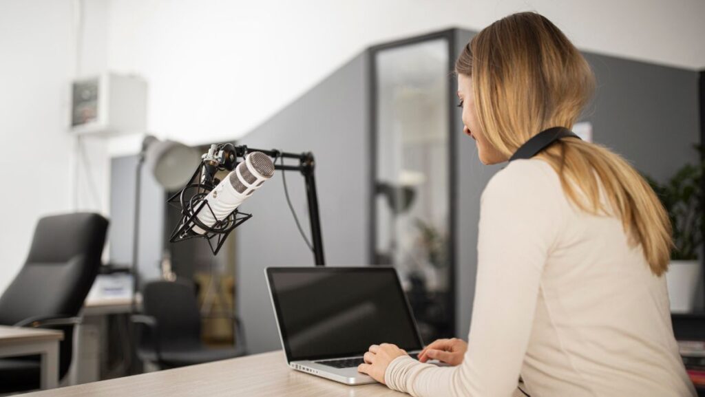 Mujer grabando frente a una laptop con micrófono