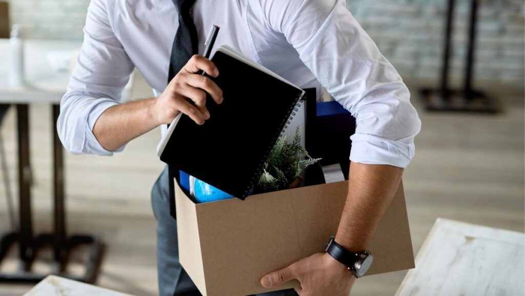 Hombre despedido cargando su caja de cosas de oficina