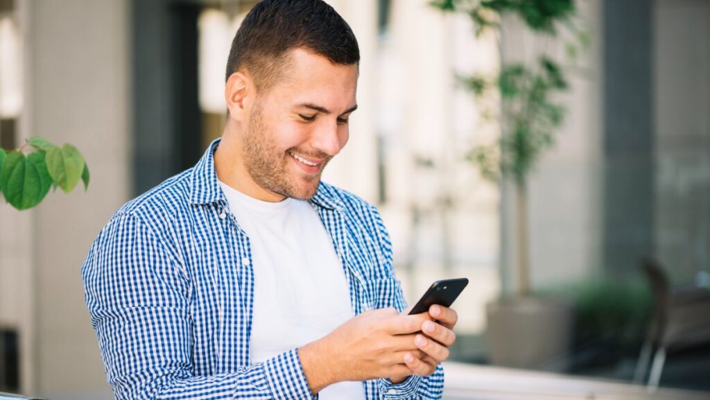 Hombre sonriendo con su celular en la mano