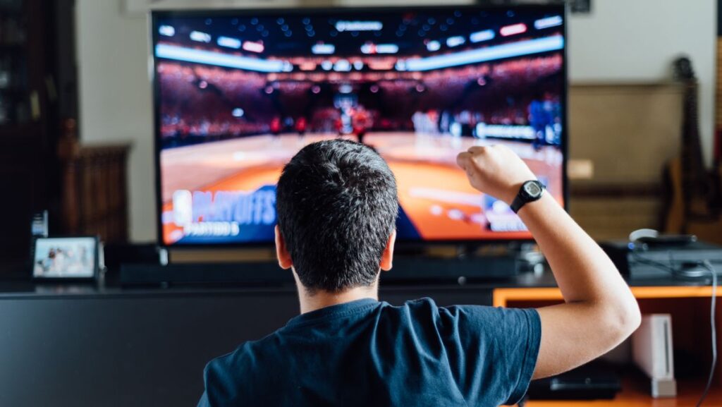 Hombre viendo partido de básquetbol en TV