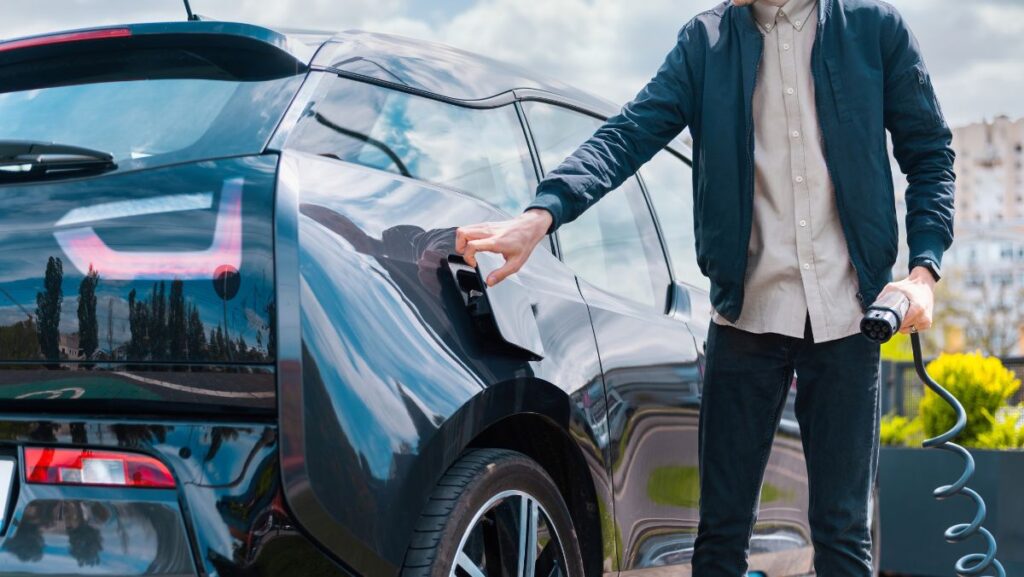 Joven cargando auto eléctrico