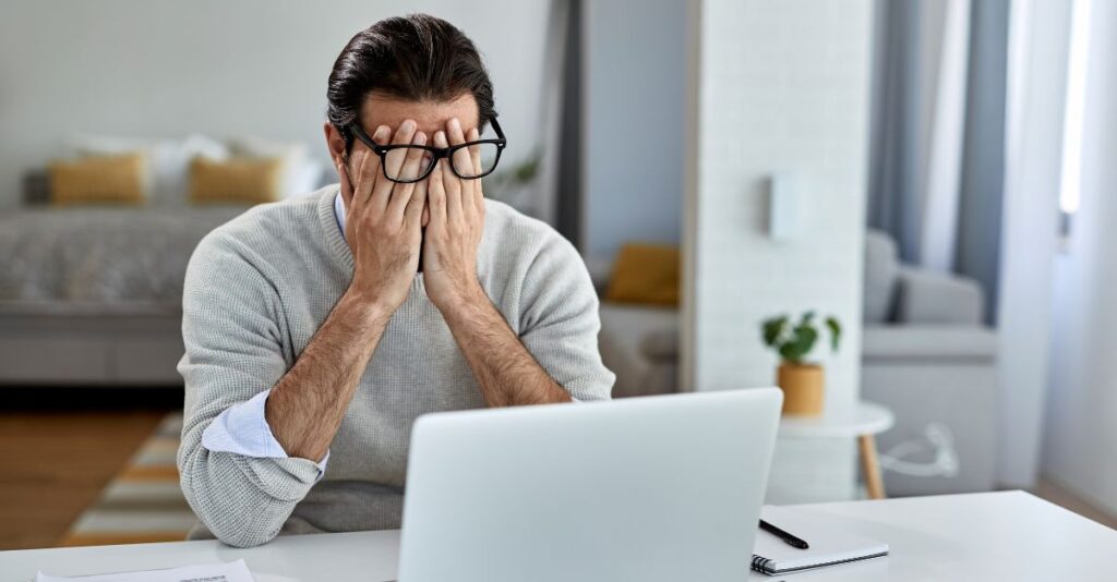 Hombre frustrado frente a laptop