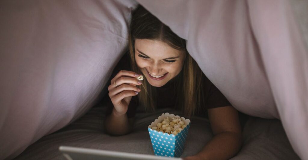 Mujer viendo tablet comiendo palomitas
