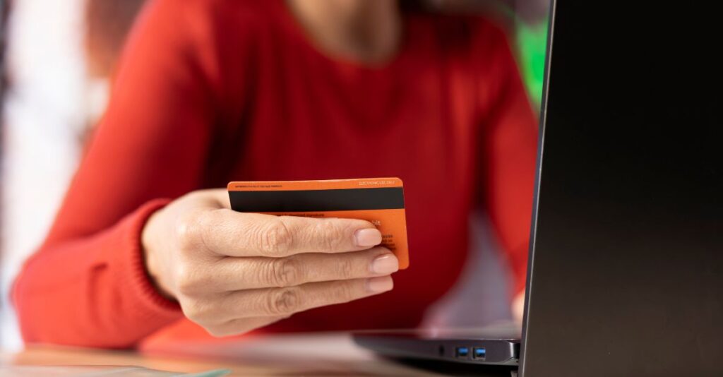 Mujer sosteniendo tarjeta pagando en una computadora