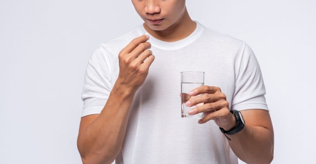 Hombre tomando pastilla con vaso de agua